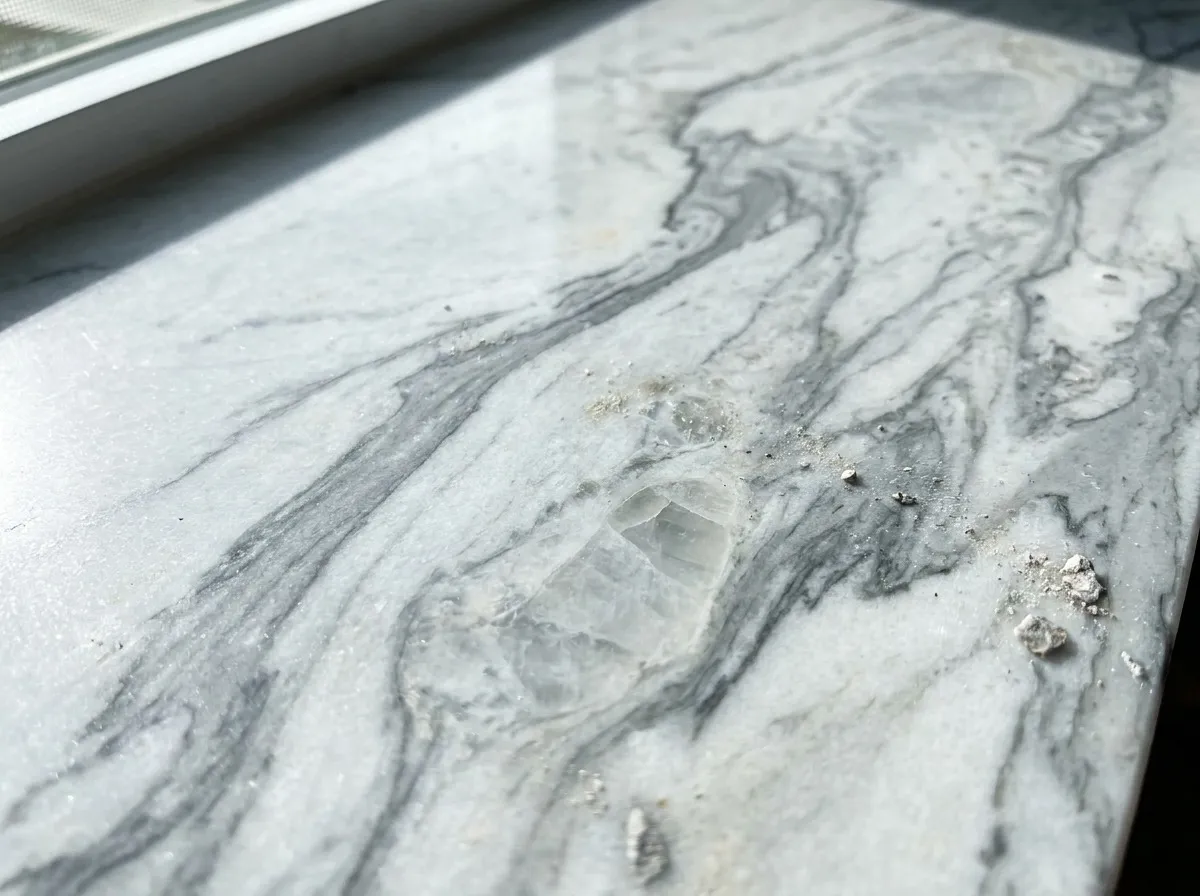 Macro detail of a polished quartzite slab showing dramatic marble-like gray veining on a hard crystalline surface.